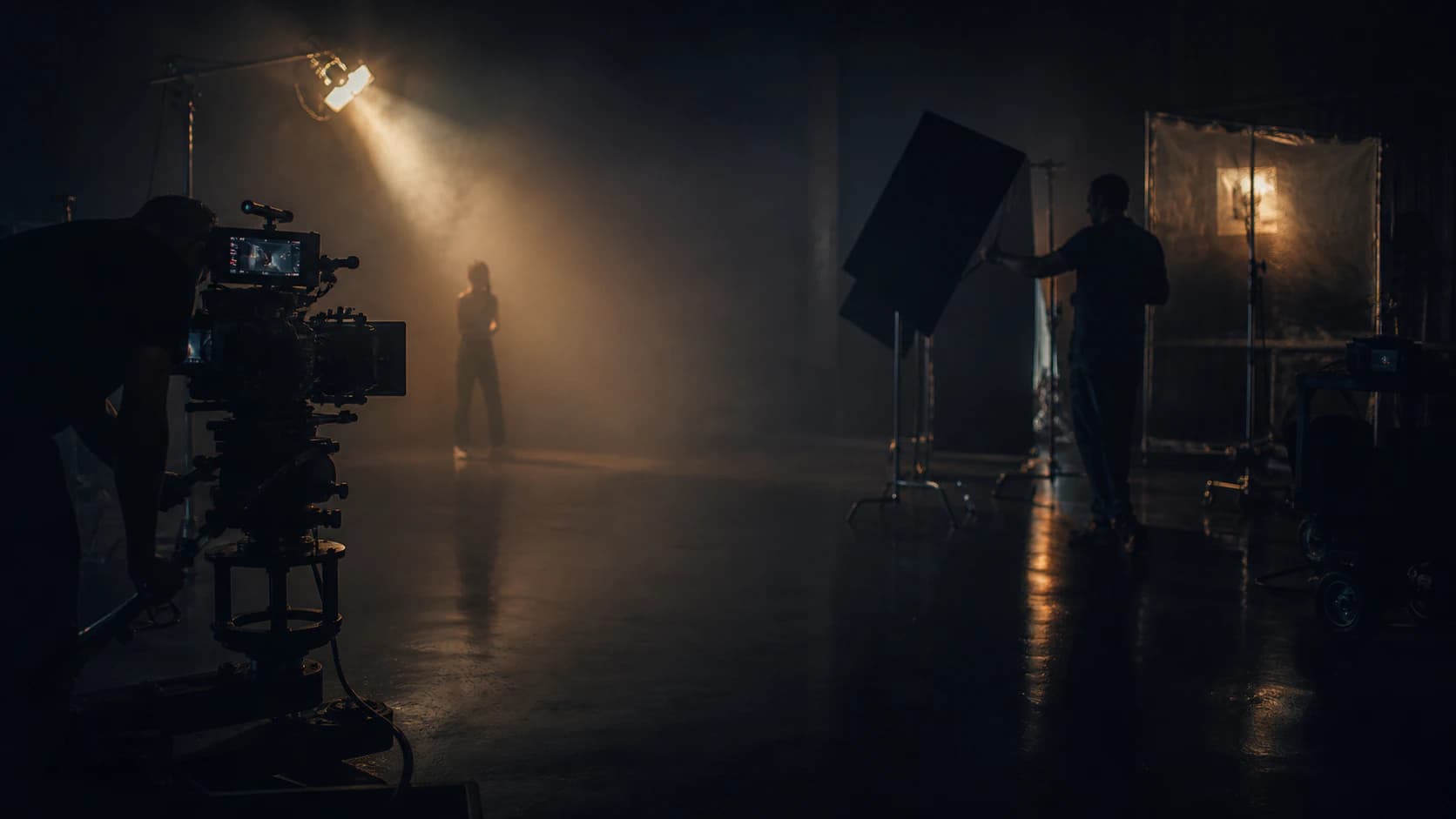Anonymous film crew shaping light around a cinema camera on set