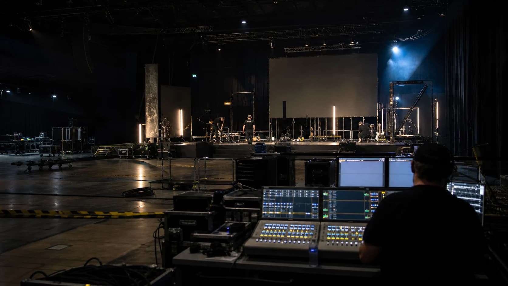 Anonymous crew preparing lighting and stage systems inside a dark event venue